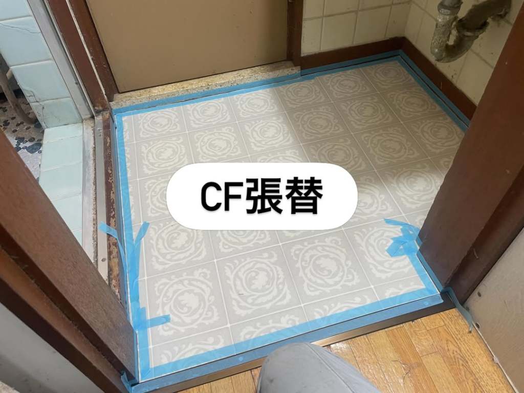 CF張替え作業中の床の写真。青いマスキングテープで囲まれた模様のあるフロアが見える。