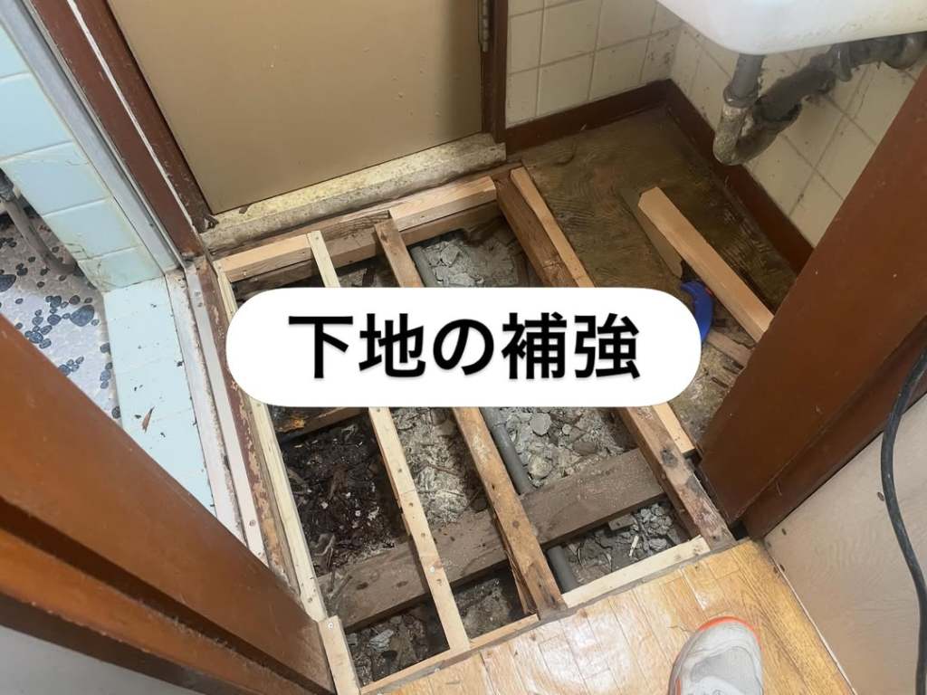 床の補強作業中の写真。剥がされたフローリングと見える土台が示されている。