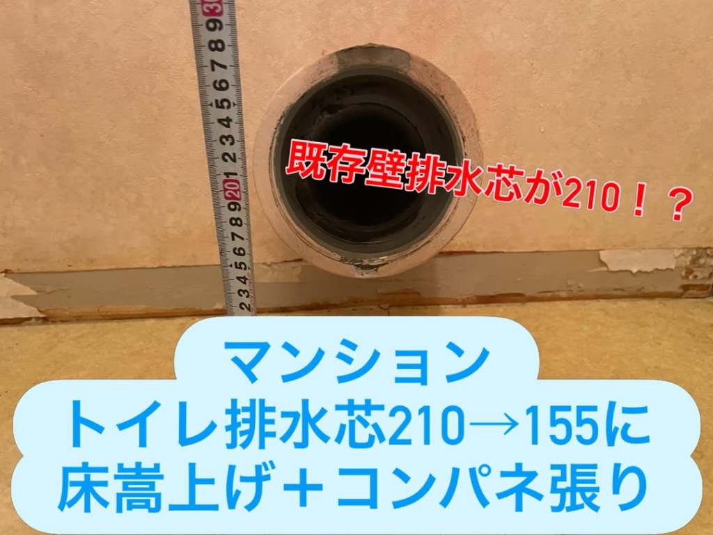 トイレ排水芯の寸法を測定している写真。210mmから155mmに変更する計画に関するメッセージが表示されています。