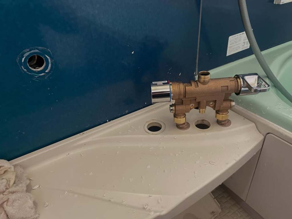 浴室の壁に取り付けられた温水器のバルブとその周囲の様子
