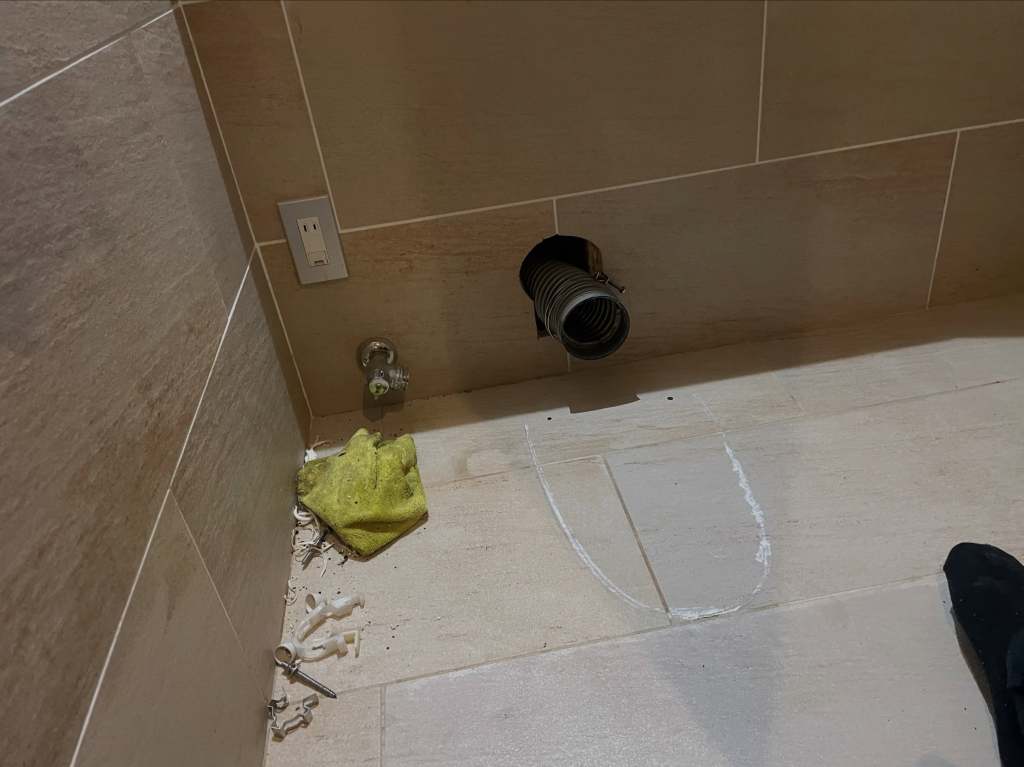 床に配管があり、周辺に掃除用のスポンジや道具が散乱している様子